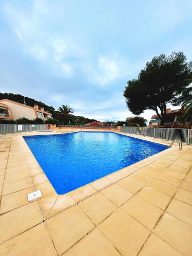 une piscine avec de l'eau bleue dans une cour dans l'établissement Le nid du Pradet - Piscine, tennis, plage à 5 min à pied, au Pradet
