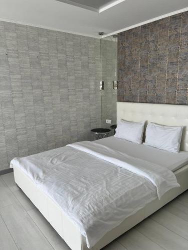 a large white bed in a bedroom with a wall at ЖК Андріївський Нова квартира в серці Тернополя in Ternopilʼ