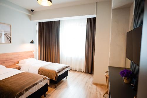 a hotel room with two beds and a window at At George`s Stay&Fly in Otopeni