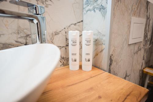 two white bottles sitting on a wooden table in a bathroom at At George`s Stay&Fly in Otopeni