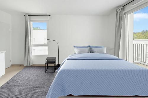 a white bedroom with a blue bed and a window at Studio lumineux avec balcon privé in Poissy