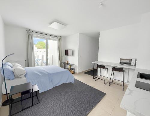 a white bedroom with a bed and a desk at Studio lumineux avec balcon privé in Poissy