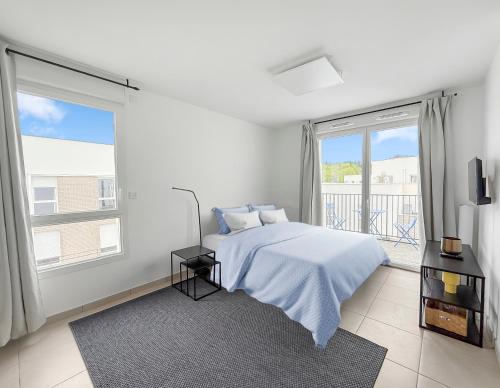 a white bedroom with a bed and a large window at Studio lumineux avec balcon privé in Poissy