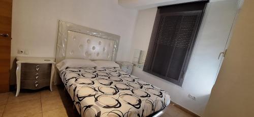 a small bedroom with a bed and a window at Apartamento Cervantes in Benetúser
