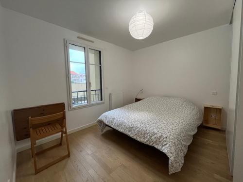 une chambre avec un lit, une chaise et une fenêtre dans l'établissement Arcachon Centre et Plage, à Arcachon
