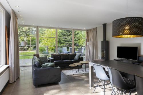 a living room with a table and chairs and a couch at Relaxen in het bos met privésauna in Holten