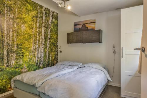 a bedroom with a bed and a window with trees at Relaxen in het bos met privésauna in Holten