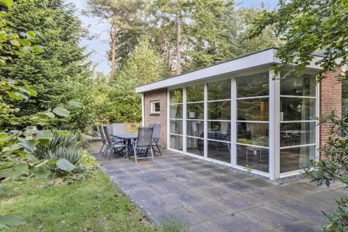 a conservatory with a table and chairs on a patio at Relaxen in het bos met privésauna in Holten