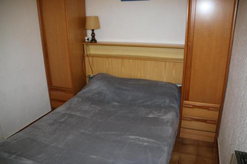 une petite chambre avec un lit avec un drap gris dans l'établissement Villa 113, Heliovillage au village naturiste, au Cap d'Agde