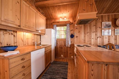 a kitchen with wooden cabinets and a white refrigerator at Hagali by Norgesbooking - cabin by the lake Næra, close to Sjusjøen in Ringsaker