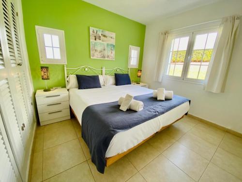 1 dormitorio con 1 cama grande y paredes verdes en SAN JAIME 5 by SOM Menorca, en Son Bou
