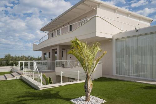 a large white house with a palm tree in the yard at Relais Villa Ottavia in Bitonto
