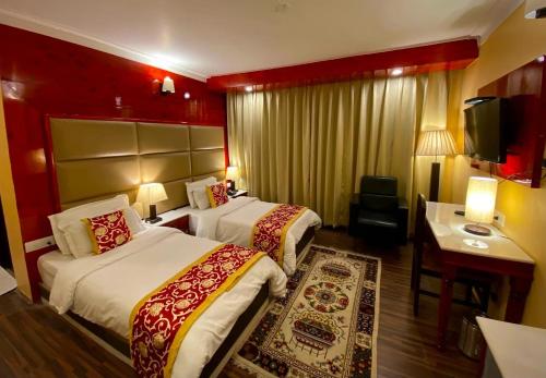 a hotel room with two beds and a desk at The Highland Mountain Resort & Spa Kargil in Kargil