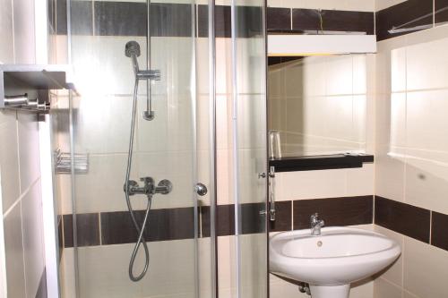 uma casa de banho com um chuveiro e um lavatório. em Belvárosi Panzió em Siófok