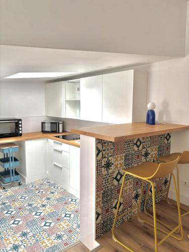 a kitchen with white cabinets and a table with a yellow chair at Maison typique au cœur du centre ville in Saint-Gilles-Croix-de-Vie