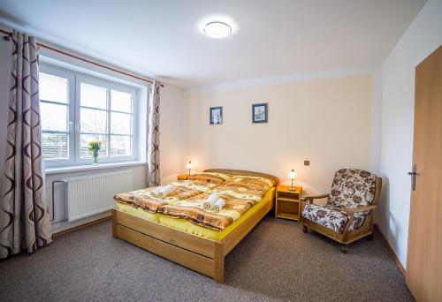 a bedroom with a bed and a chair and a window at Pension Jana in Český Krumlov