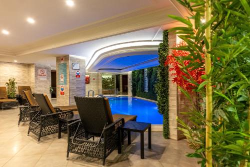a hotel lobby with a pool and chairs and plants at Askoc Hotel & SPA in Istanbul