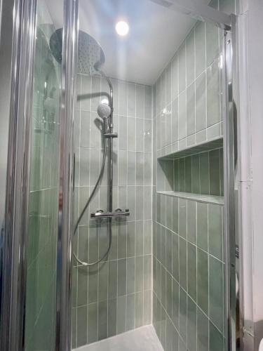La salle de bains est pourvue d'une douche et de carrelage vert. dans l'établissement Cozy renovated studio, à Montrouge
