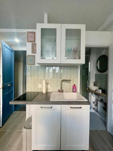 une cuisine avec des armoires blanches et un évier dans l'établissement Cozy renovated studio, à Montrouge