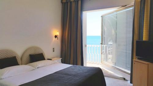a bedroom with a bed and a balcony with the ocean at Hotel Ristorante Maga Circe in San Felice Circeo