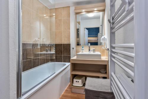 une salle de bain avec une baignoire, un lavabo et un miroir dans l'établissement Résidence Les Terrasses Du Soleil D'or - Studio 4 personnes au coeur des Orres 1800 MAE-4581, aux Orres