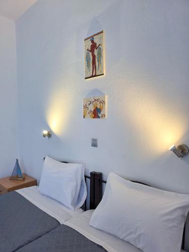 a bedroom with a bed with white sheets and two pictures on the wall at Calypso Heaven in Santorini