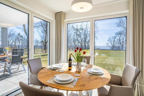 a dining room with a table and chairs and large windows at Terrassenwohnung "Haffromantik" in Garz