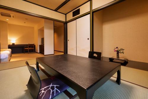 a room with a table and chairs and a bedroom at Hotel Yumeshizuku in Minami Aso