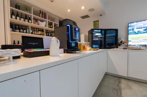 a bar with a counter with a refrigerator at Le B Complexe Hôtel in Lozanne