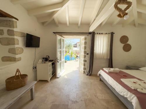 a bedroom with a bed and a tv and a door at La Grenadine Hotel in Alacati