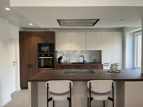 a kitchen with a island with bar stools at Durbuy, l Olivier, Maison charmante 4 façades en pierre du pays in Durbuy