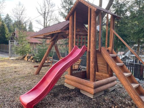 a wooden playground with a slide in a yard at Casa Sofia in Băile Homorod