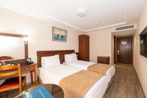 a hotel room with two beds and a desk at Askoc Hotel & SPA in Istanbul