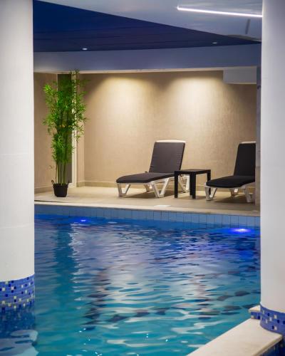 two chairs and a table next to a swimming pool at Doanesia Premium Hotel & Spa in Tirana