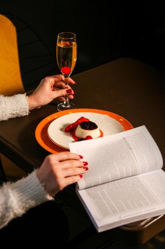 a person sitting at a table with a book and a glass of wine at Doanesia Premium Hotel & Spa in Tirana