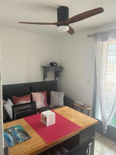 - un salon avec une table et un ventilateur de plafond dans l'établissement Studio Loggia Mas de la Pinède parking, à Valras-Plage