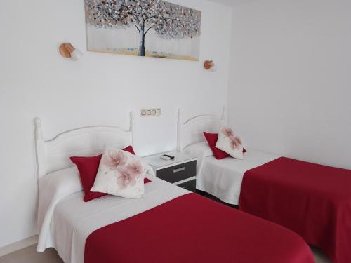 two beds in a room with red and white sheets at Hostal Arcos Beach Chipiona in Chipiona
