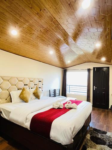 a bedroom with a large bed with a wooden ceiling at Ambrosia Grand in Shimla