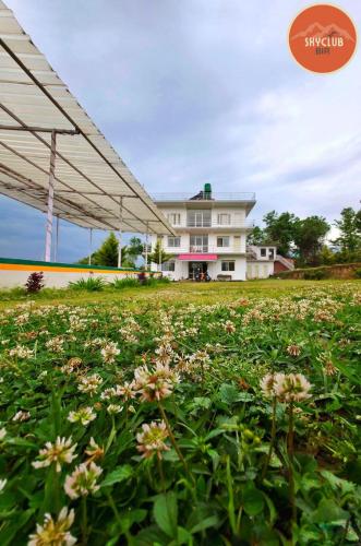 a field of flowers with a building in the background at Sky Club Bir Hospitality in Bīr