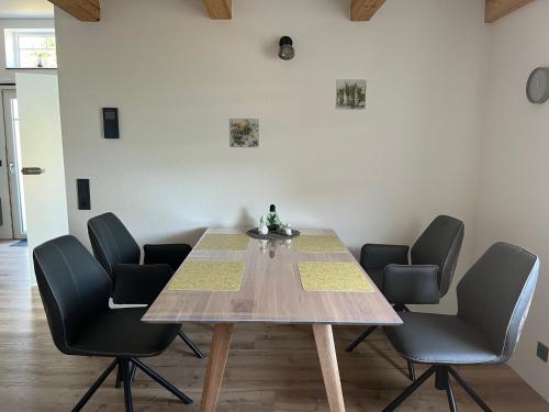 a dining room with a table and four chairs at Haus Mariechen 5-Sterne-DTV-Ferienwohnung in der Nähe zum Silbersee mit Balkon & Sauna in Frielendorf