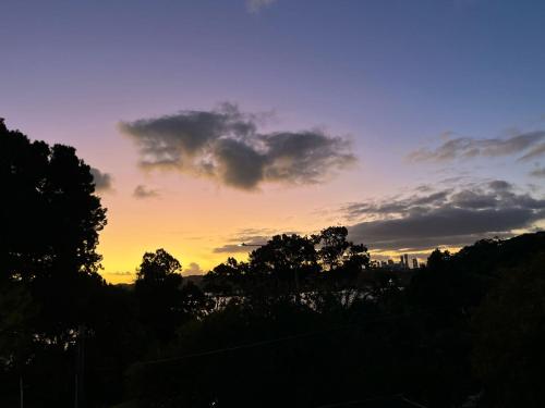 a sunset with trees and a city in the background at Rumah Singgah in Kampong Tengah