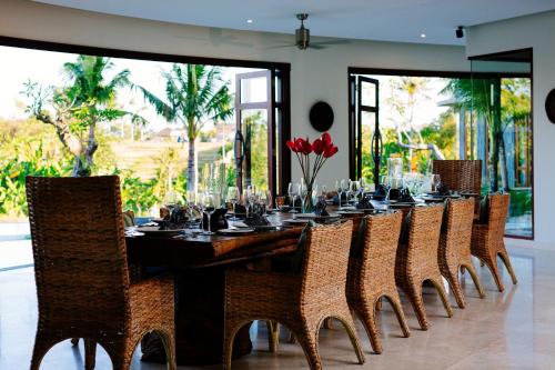 a dining room with a long table and chairs at Umah Daun by Nakula in Canggu