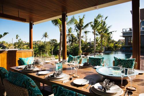 a long wooden table with wine glasses on a patio at Umah Daun by Nakula in Canggu