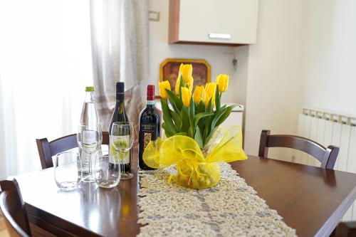 a dining room table with wine bottles and yellow flowers at Il Cantico Suite in Assisi