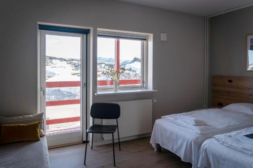 a bedroom with a bed and a chair next to a window at HOTEL SØMA Ilulissat in Ilulissat