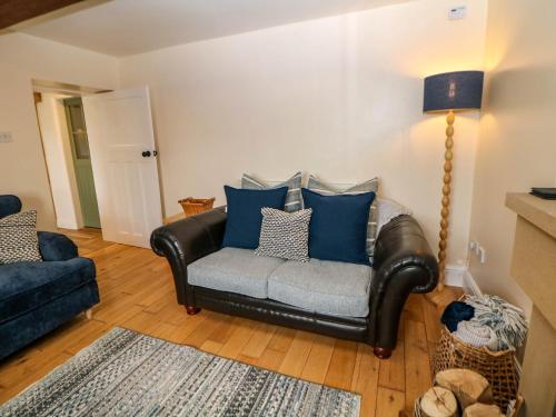 a leather couch with blue pillows in a living room at Heathylee in Longnor