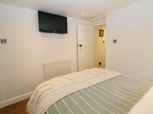a bedroom with a tv on a white wall at Heathylee in Longnor