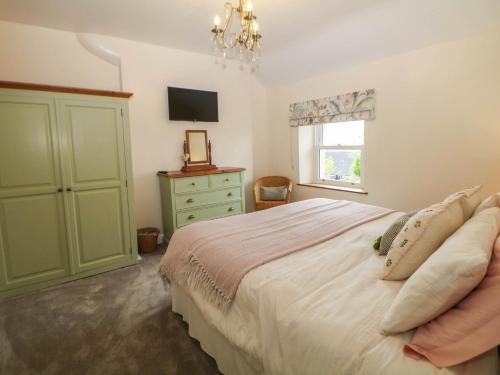 a bedroom with a bed and a dresser and a television at Heathylee in Longnor