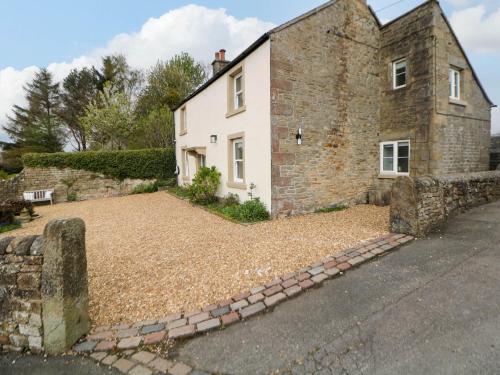 an old stone house with a gravel driveway at Heathylee in Longnor
