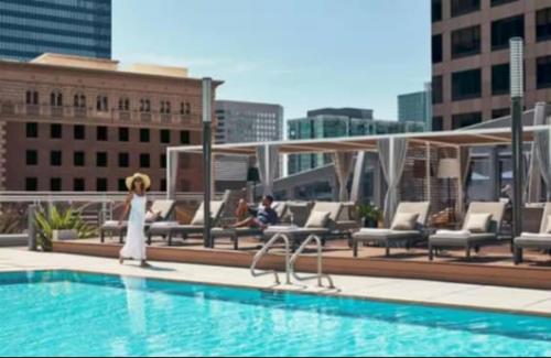 a woman standing next to a swimming pool on a building at Cozy 3BR High Rise with Pool with great views in Los Angeles